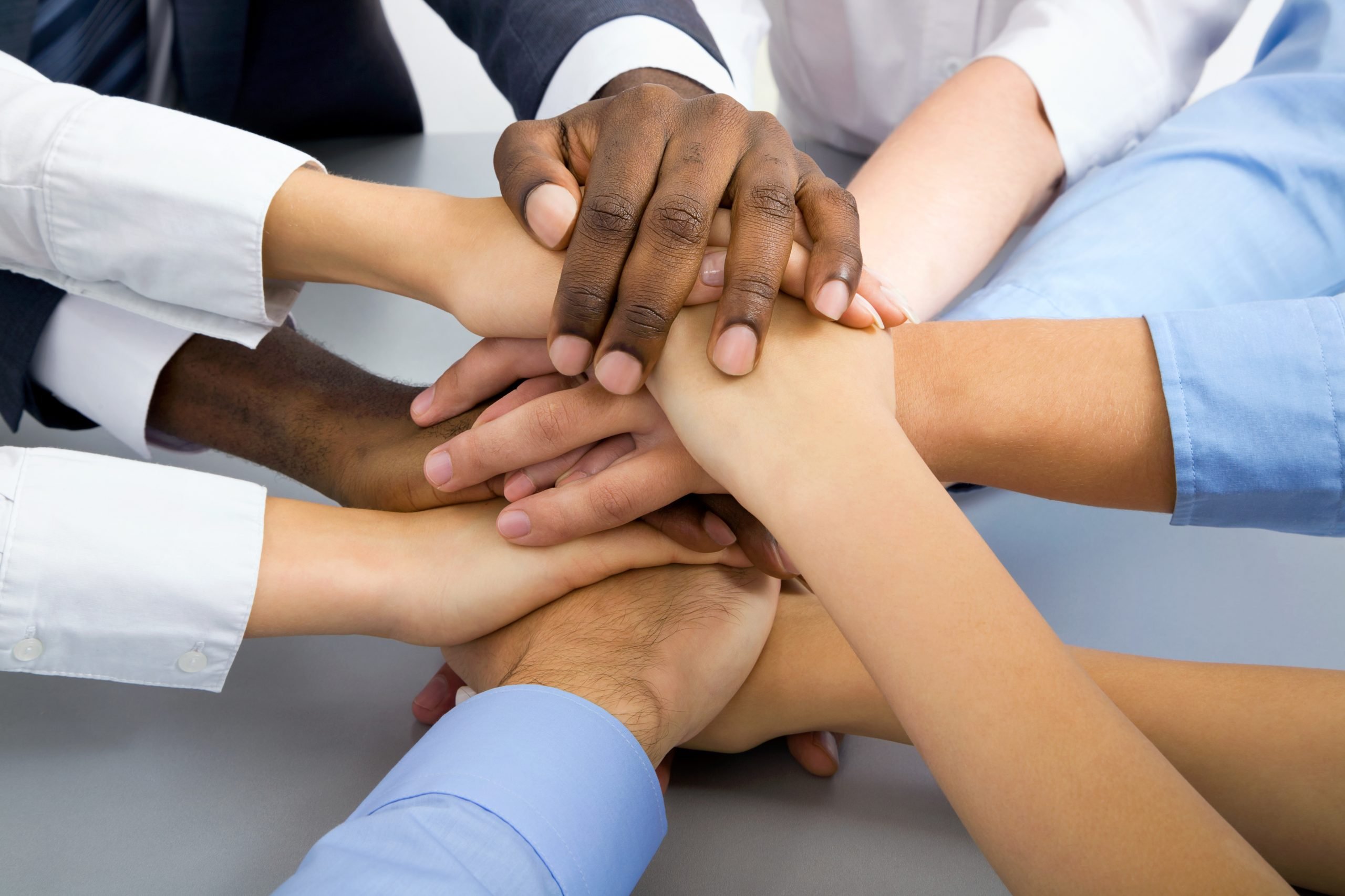 several hands overlapping dressed in business formal attire